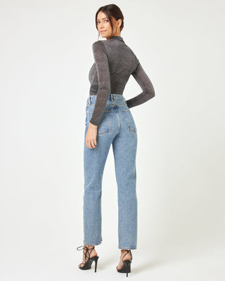 Back view of a model wearing the LSPACE Shimmer Long Sleeve in black, showing the sheer metallic sparkle fabric across the back and fitted long sleeves, styled with straight-leg jeans.